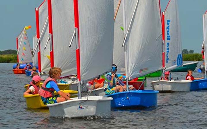 Kinderen varen in een Optimist zeilboot